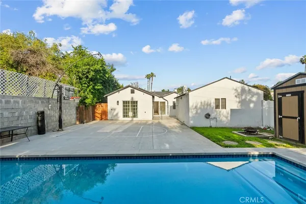a front view of house with yard outdoor seating and trees in the background