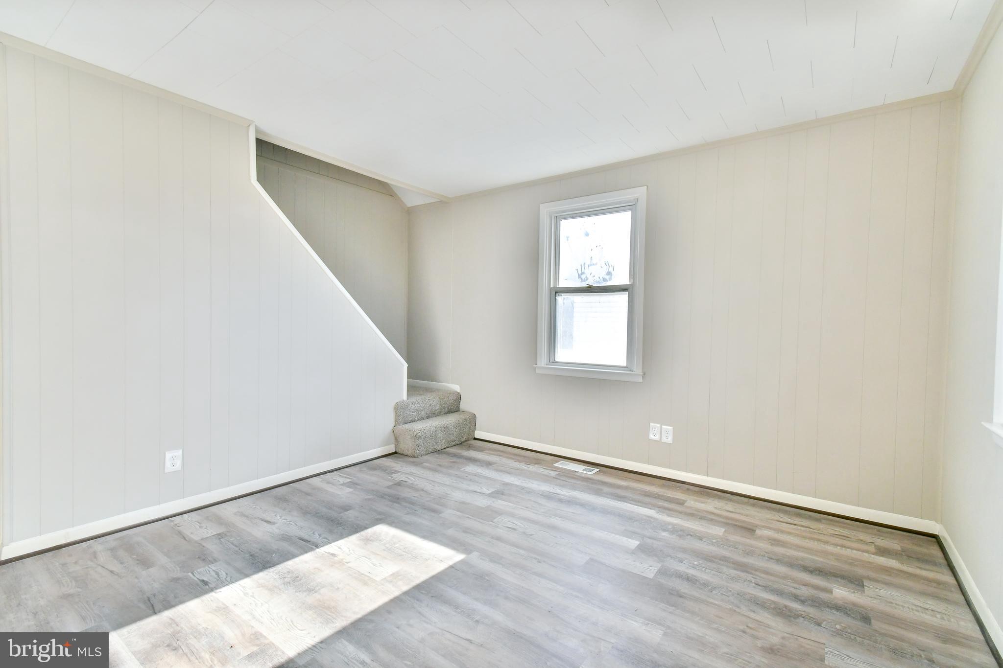 7618 Spruce Road Baltimore, MD 21222 - Photo 5 of 42 an empty room with wooden floor and windows