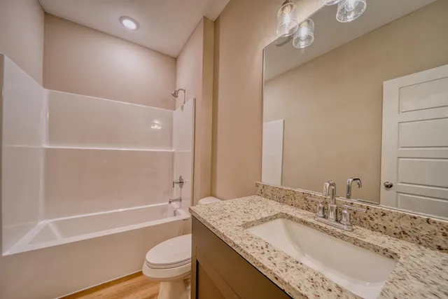 a bathroom with a granite countertop sink a toilet and a large mirror
