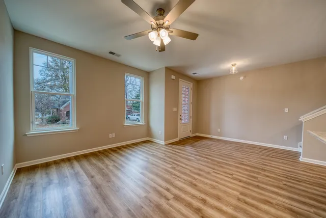a view of an empty room with window and wooden floor