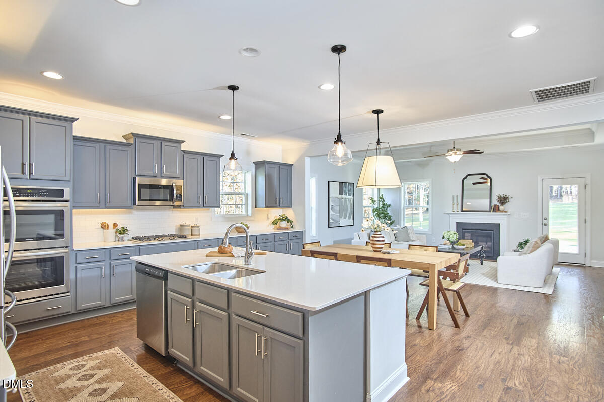 8600 Rowan Oak Court Wake Forest, NC 27587 - Photo 7 of 42 a open kitchen with stainless steel appliances granite countertop a stove top oven a sink dishwasher a dining table and chairs with wooden floor