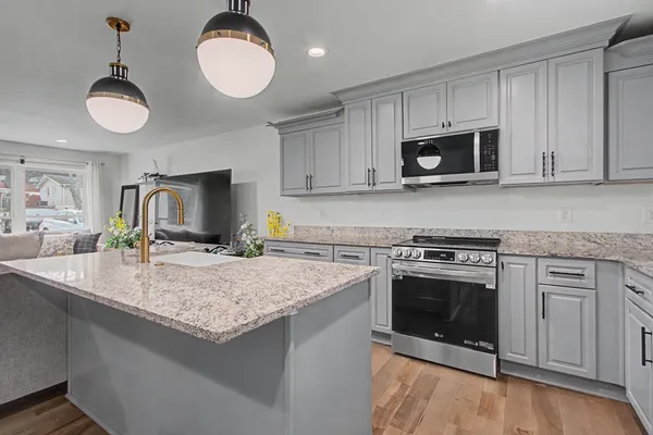 a kitchen with stainless steel appliances granite countertop a stove a sink and a microwave