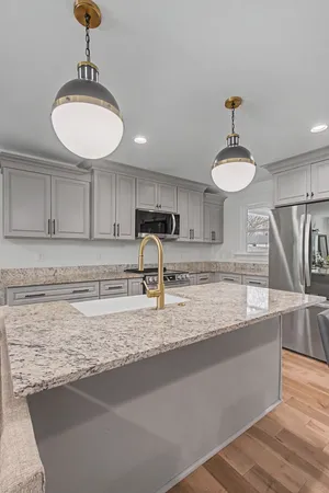 a kitchen with stainless steel appliances granite countertop a sink a stove and a wooden floors