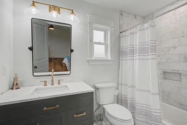 a bathroom with a sink vanity granite toilet and a mirror