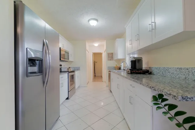a large kitchen with a refrigerator a sink and cabinets