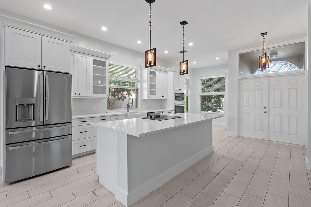 168 South Hampton Drive Jupiter, FL 33458 - Photo 5 of 33 a large kitchen with granite countertop a white refrigerator oven a sink dishwasher and white cabinets with wooden floor