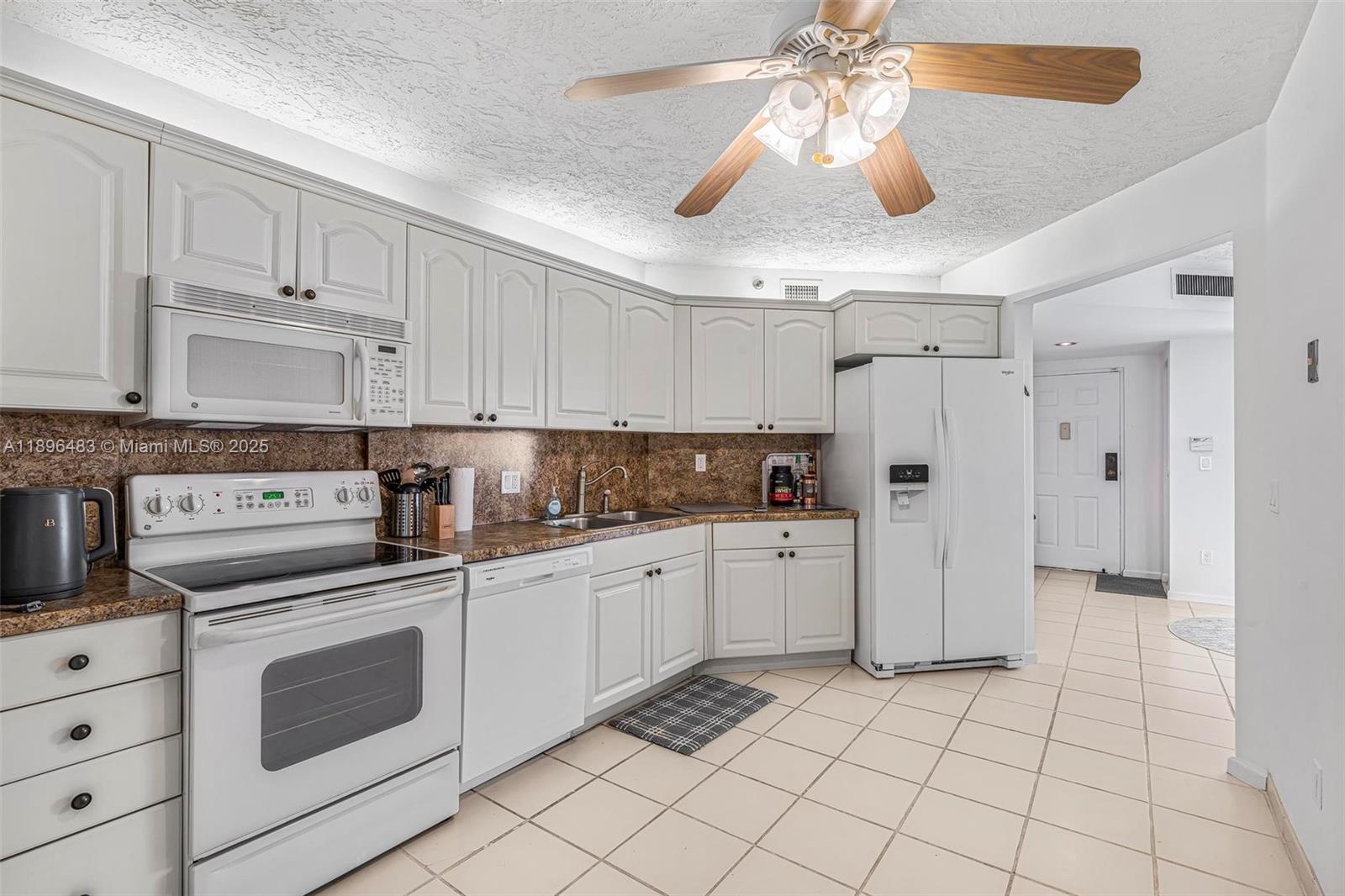 7507 La Paz Boulevard, Unit 407 Boca Raton, FL 33433 - Photo 10 of 34 a kitchen with white cabinets and white appliances