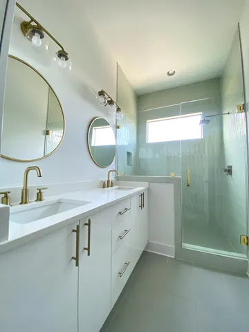 a bathroom with a double vanity sink mirror and shower