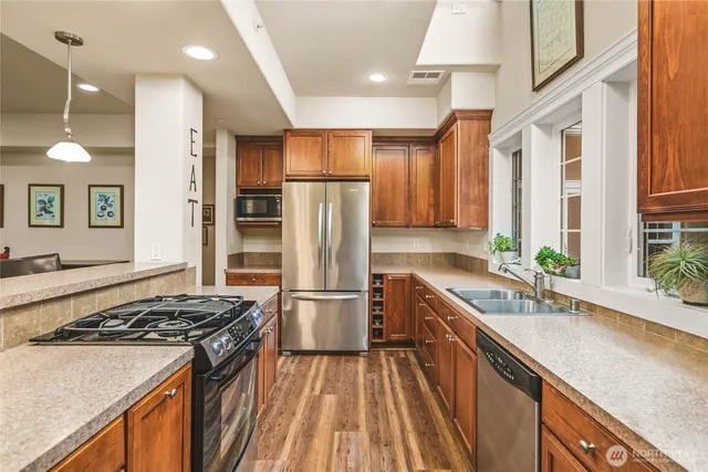 a kitchen with kitchen island granite countertop a sink stainless steel appliances and cabinets