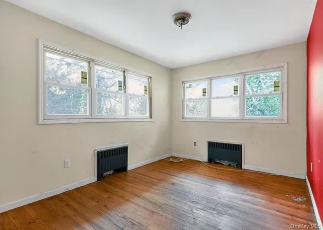 an empty room with windows fireplace and wooden floor