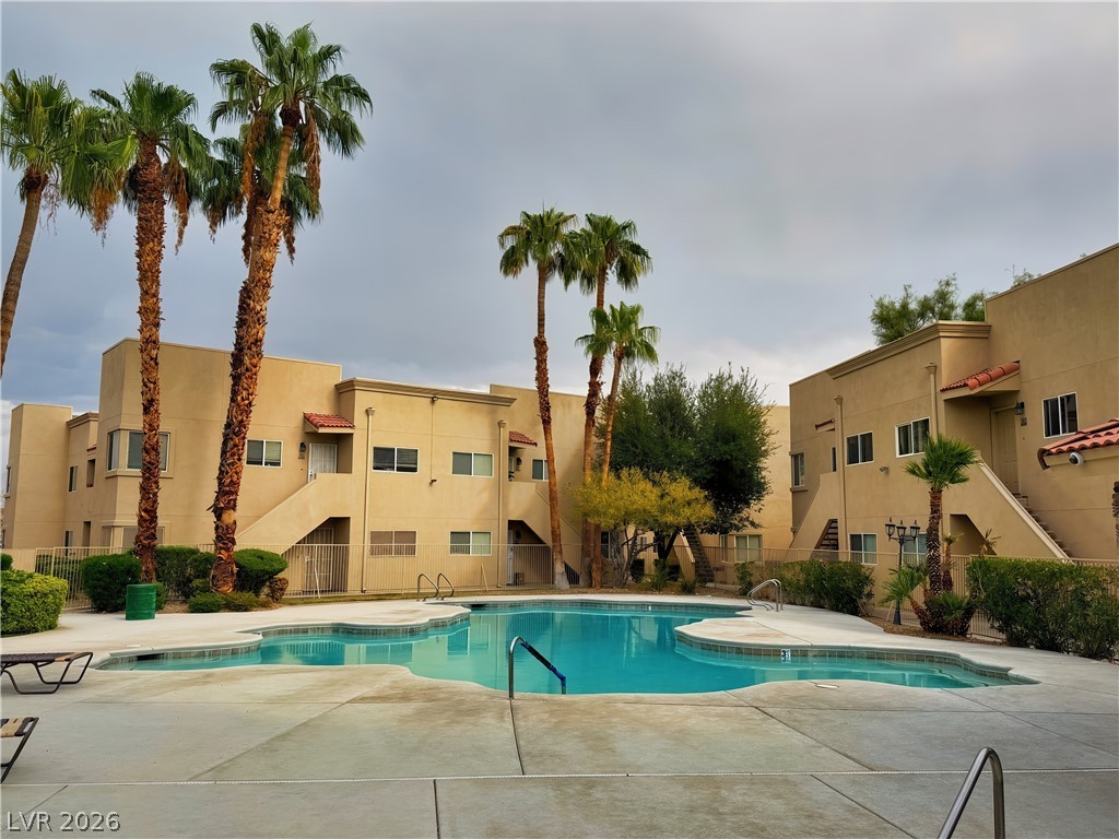 1852 North Decatur Boulevard, Unit 101 Las Vegas, NV 89108 - Photo 8 of 45 A sparkling community pool sits framed by tall palm trees and modern residential buildings.