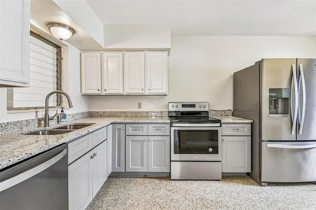 a kitchen with stainless steel appliances granite countertop a sink stove and refrigerator