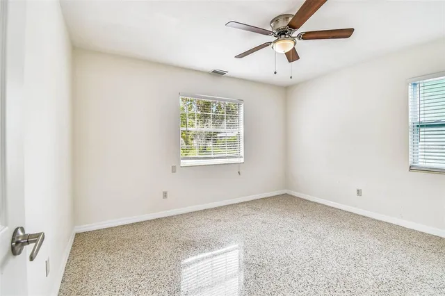 an empty room with windows and fan