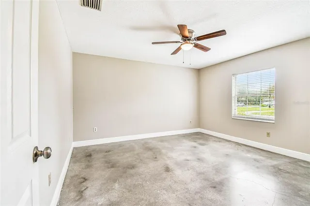 an empty room with fan and windows