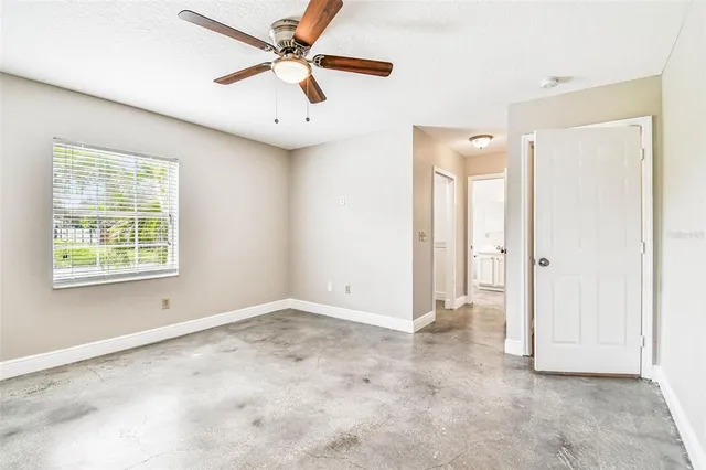 an empty room with windows and fan
