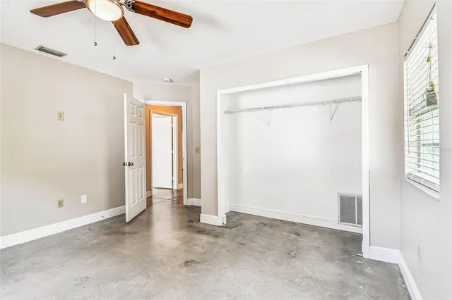 an empty room with fan and windows