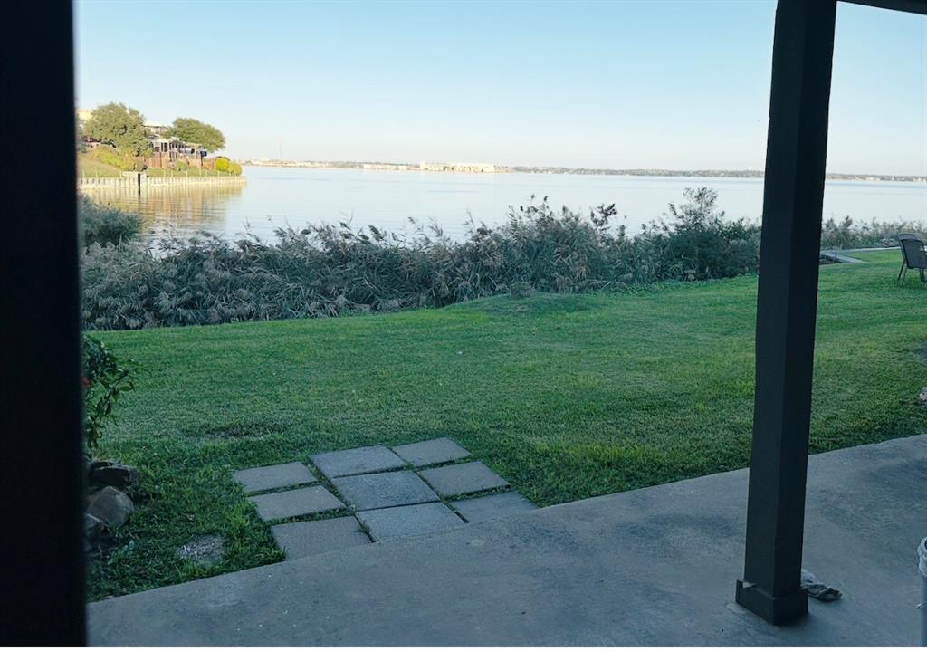 4472 Chaha Road, Unit 104 Garland, TX 75043 - Photo 3 of 5 Waterfront backyard featuring a concrete patio, stepping stones, and a grass lawn extending to the water's edge