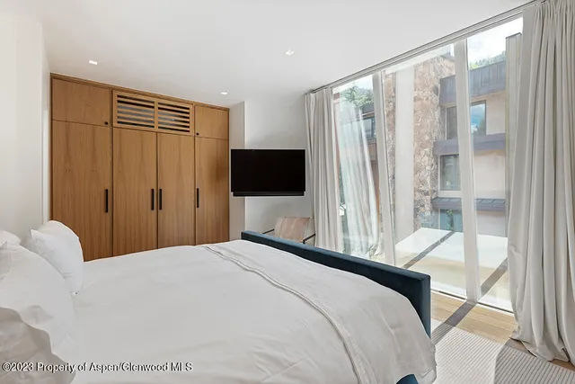 a bedroom with a large bed and a flat tv screen next to a window