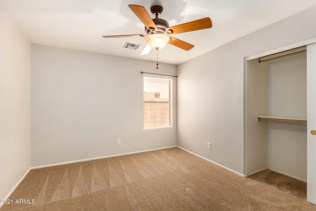 an empty room with window and ceiling fan