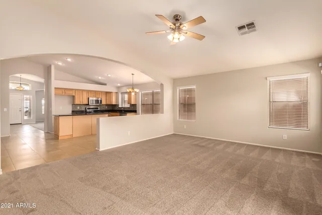 a view of an empty room with kitchen and window
