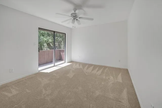 an empty room with a chandelier fan and windows