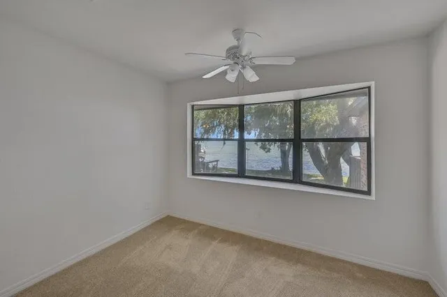 an empty room with window and ceiling fan