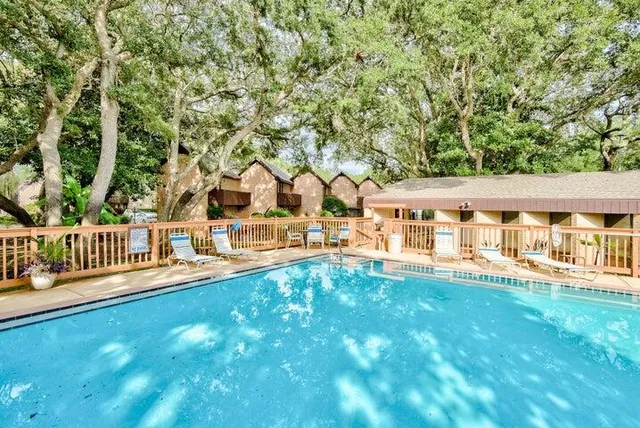 swimming pool view from a balcony with large trees