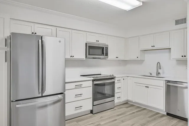 a kitchen with white cabinets and stainless steel appliances