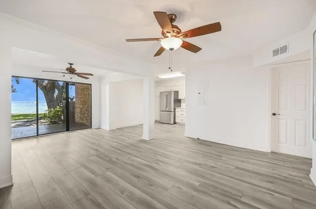 a view of an empty room with wooden floor and a ceiling fan