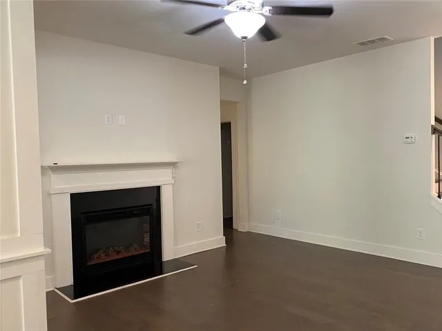 an empty room with a fireplace and chandelier fan