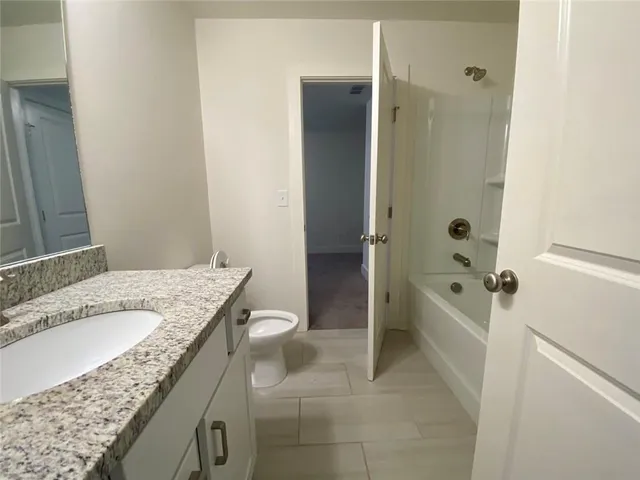 a bathroom with a granite countertop sink a toilet and shower