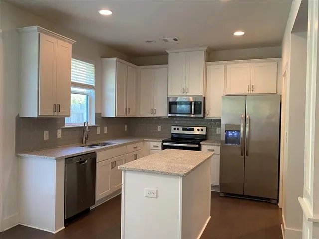 a kitchen with stainless steel appliances a sink stove refrigerator and cabinets