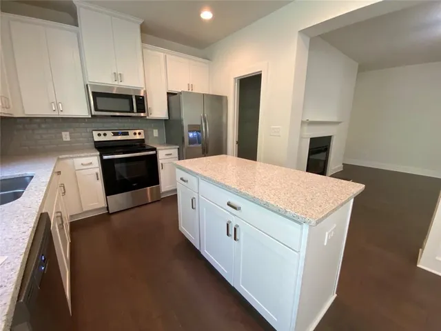 a kitchen with granite countertop white cabinets and stainless steel appliances