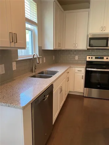 a kitchen with stainless steel appliances granite countertop a sink a stove and a microwave