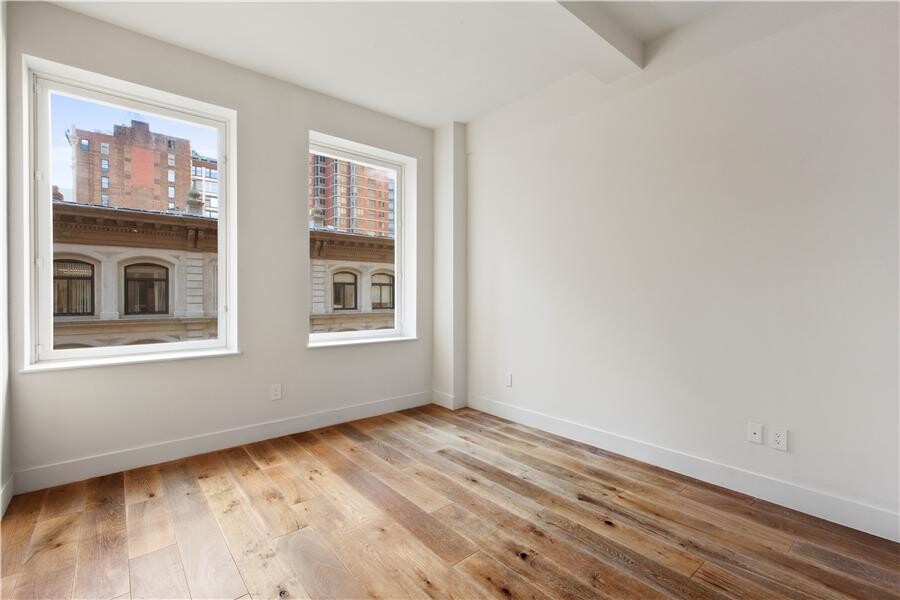 93 Worth Street, Unit 602 Manhattan, NY 10013 - Photo 5 of 8 a view of an empty room with a window and wooden floor