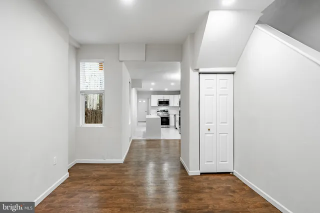 a view of a hallway with wooden floor and a bathroom