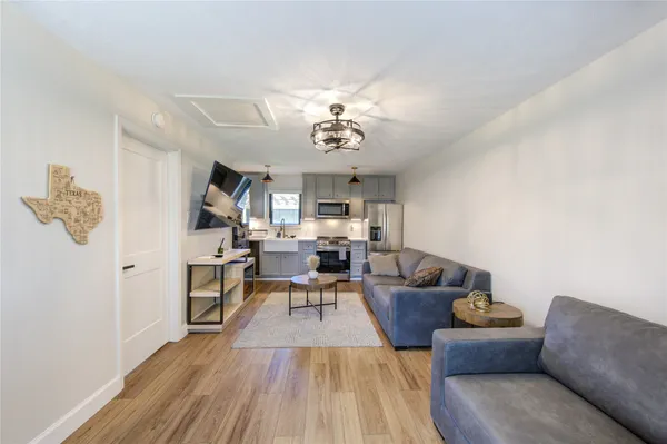 a living room with furniture kitchen view and a chandelier