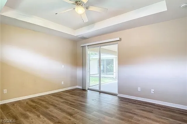 an empty room with wooden floor and fan