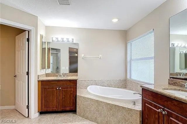 a bathroom with a granite countertop sink a toilet a mirror and bathtub