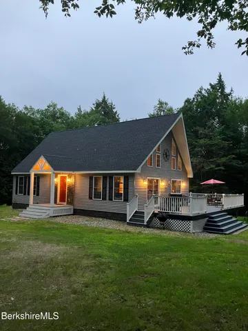 a front view of a house with a garden and trees