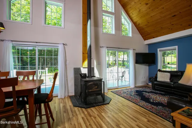 a living room with furniture floor to ceiling window hardwood floor and a flat screen tv
