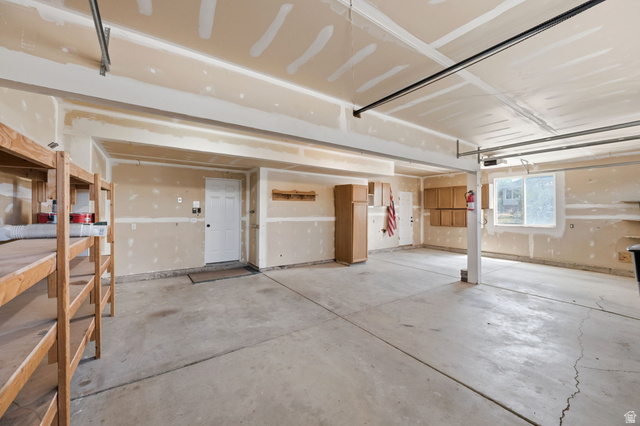3732 Campbell Road Tooele, UT 84074 - Photo 19 of 69 Spacious garage with concrete flooring, multiple built-in storage shelves, interior access door, and a prominent window