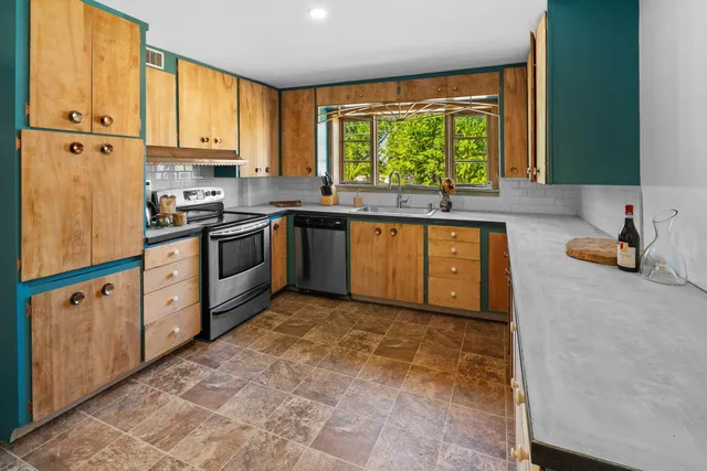 a kitchen with stainless steel appliances granite countertop a stove a sink and a refrigerator