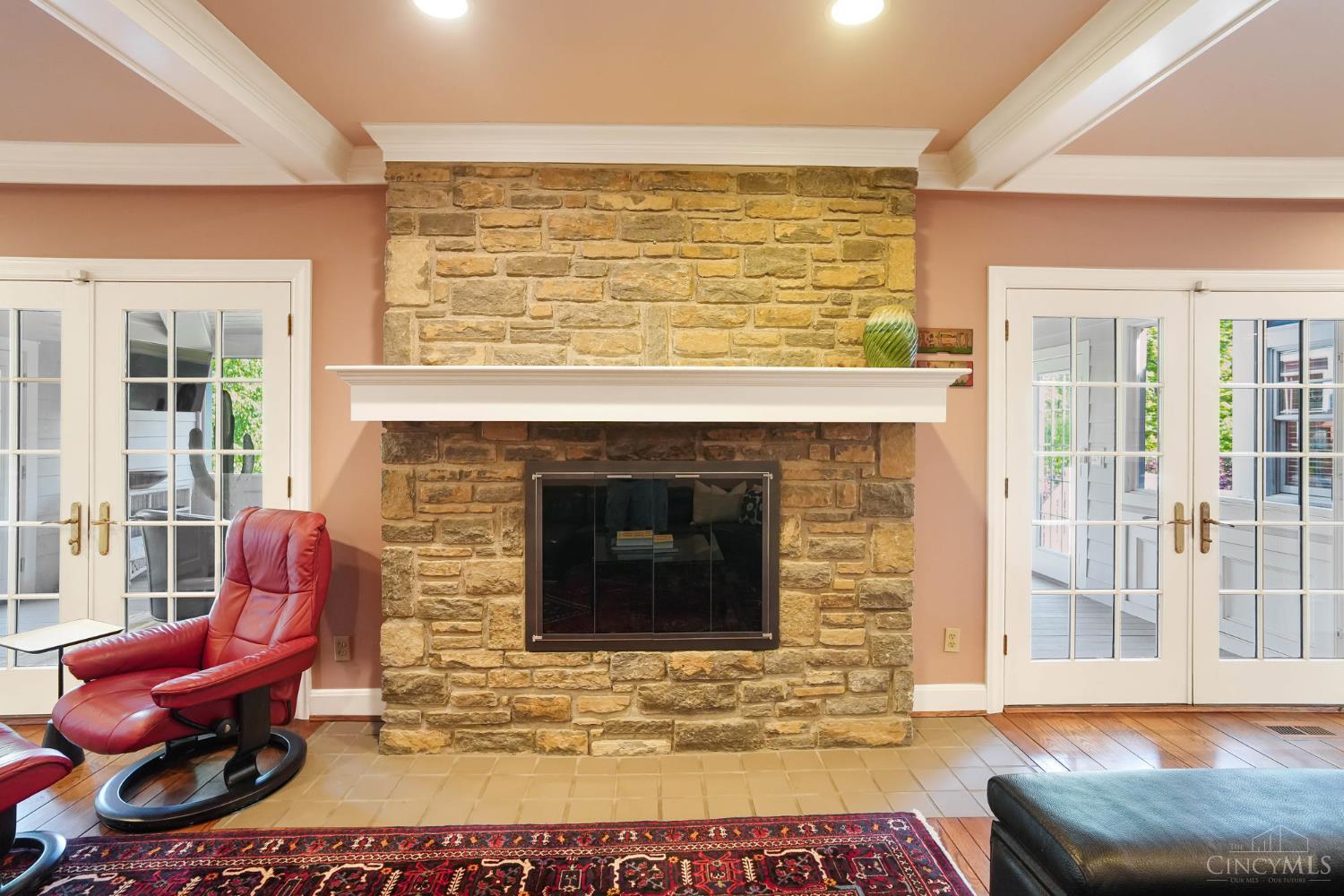2780 Walsh Road Cincinnati, OH 45208 - Photo 6 of 68 This warm and inviting family room is designed for everyday living and effortless entertaining—anchored by a striking stone fireplace and framed by rich hardwood floors and classic millwork. The generously scaled layout offers multiple seating areas, seamless flow to adjacent spaces and French doors that invite in natural light while opening to outdoor living. Custom built-ins add both function and charm, completing this comfortable yet refined gathering space.