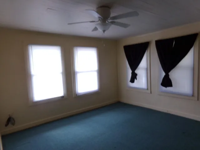 an empty room with a window and a ceiling fan