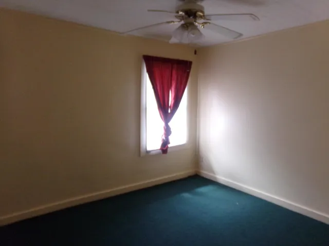 an empty room with a window and a ceiling fan