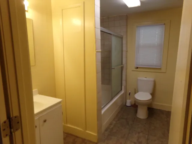 a bathroom with a granite countertop sink and a toilet