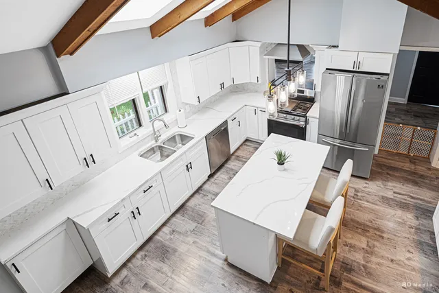 a kitchen with stainless steel appliances a refrigerator a stove a sink dishwasher and white cabinets