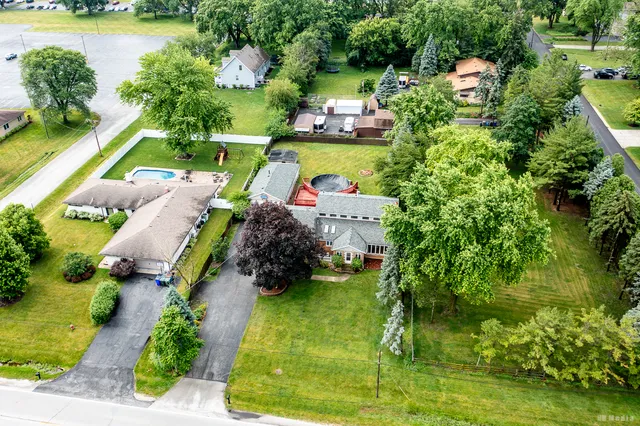 an aerial view of a house with swimming pool a patio and yard