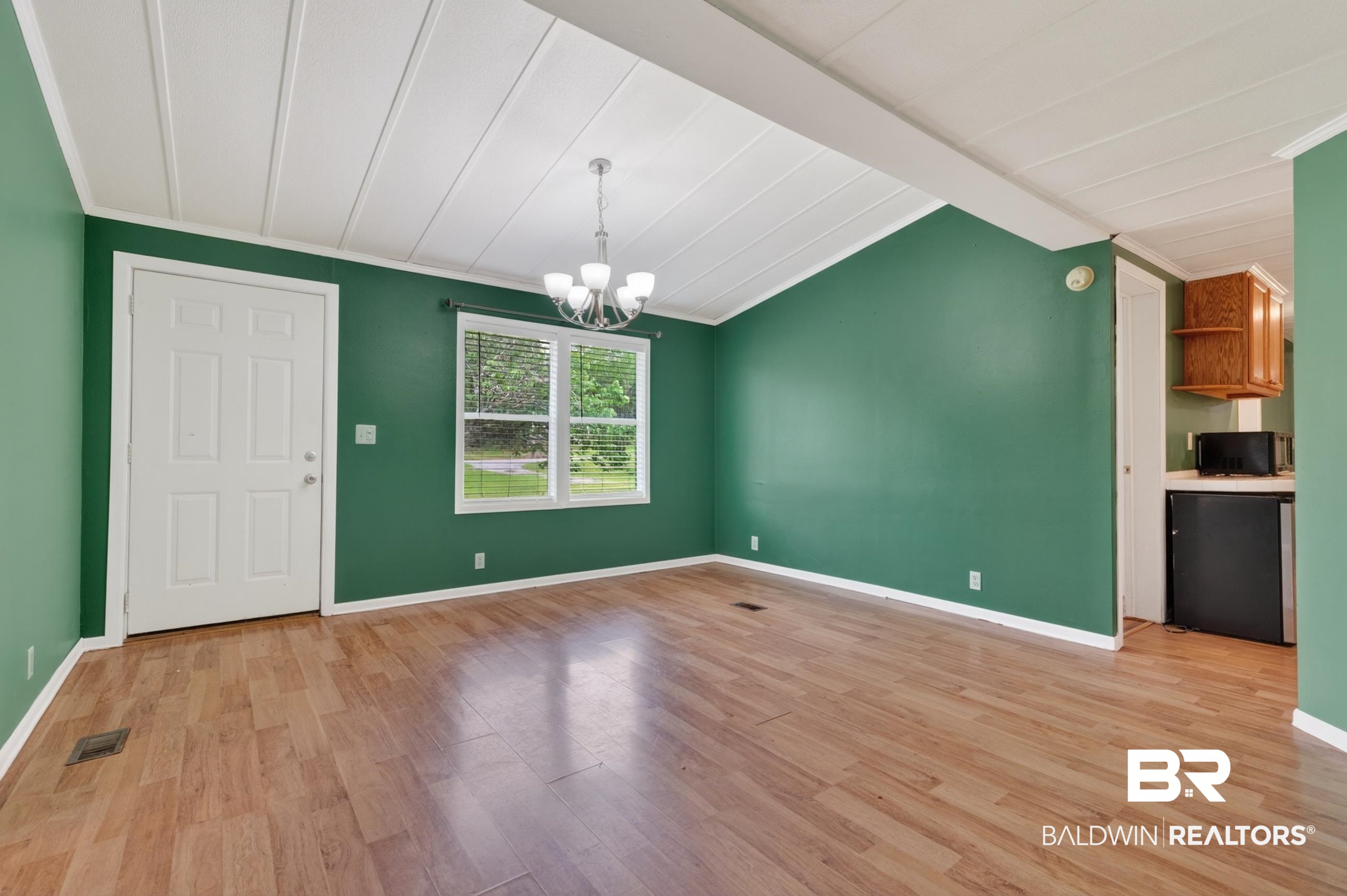 24903 Patterson Road Robertsdale, AL 36567 - Photo 29 of 57 Spacious room featuring wood-finish flooring, a white paneled door, and a multi-pane window with white blinds